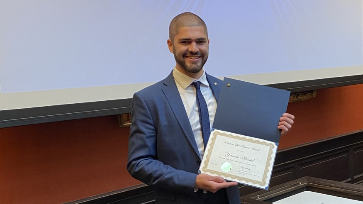 Young man wearing a blue suit holding an award certificate