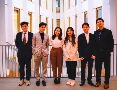 Six students, four men and two women, in business dress