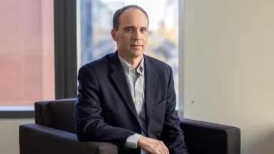 'Christopher Gaffney, PhD, Associate Clinical Professor of Decision Sciences & MIS sitting in chair in front of window