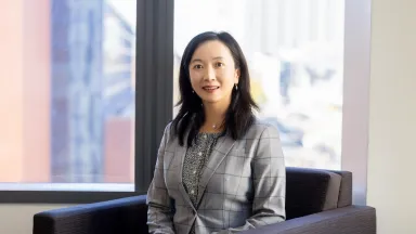 Headshot of Yanliu Huang, PhD, Associate Professor of Marketing sitting in chair in front of window