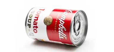 A can of Campbell's tomato soup lying on its side with its red label visible