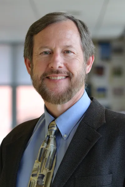 A professional photograph of the speaker, Karl Hausker, PhD.