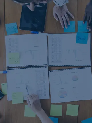 Charts, Post-It Notes, and Computers on a Table as Students Collaborate